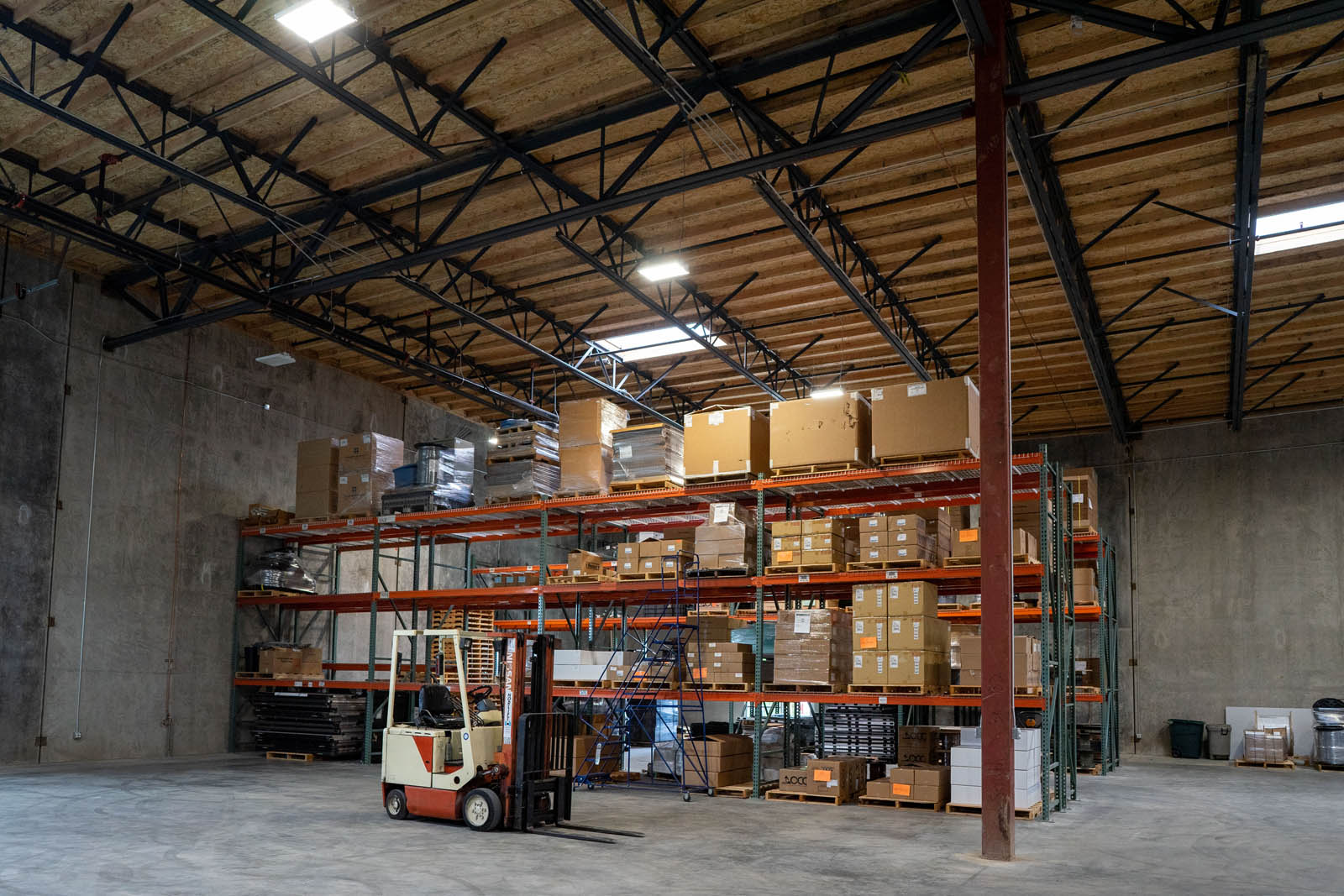 forklift in front of boxes on shelves in warehouse facility